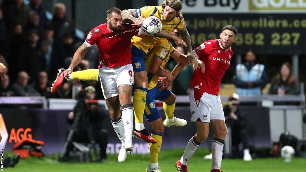 Wrexham striker Ollie Palmer competes with Mansfield defender Aden Flint