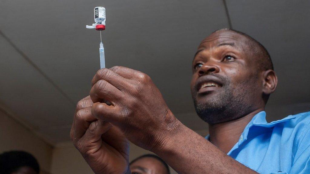 Man with syringe getting ready to adminster malaria vaccine