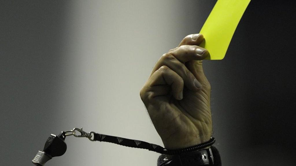 A referee showing a yellow Card