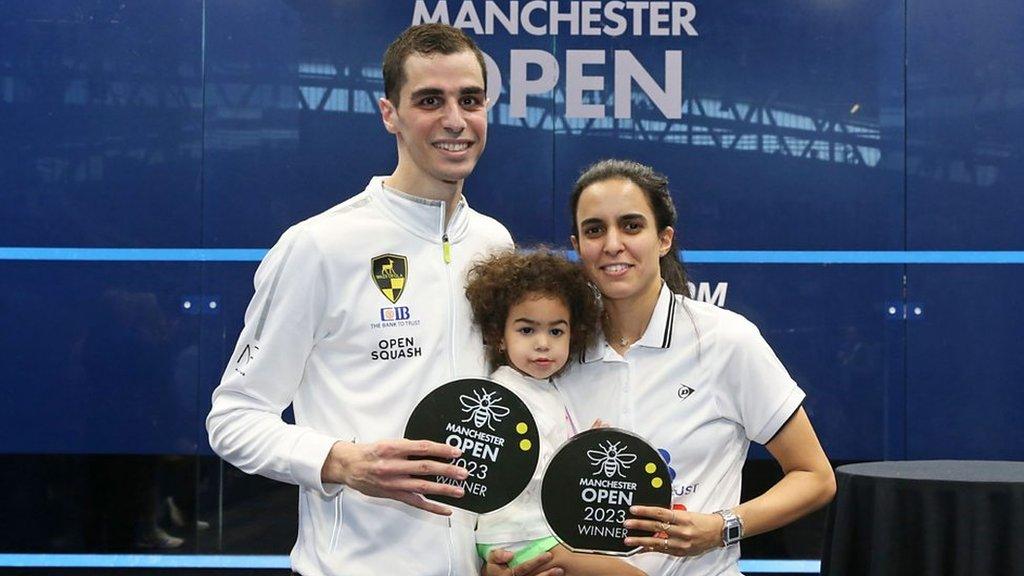 Ali Farag and Nour El Tayeb hold up their trophies at the Manchester Open with daughter Farida between them