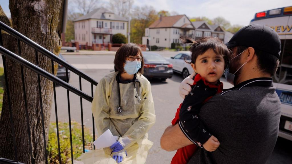 Syed Kamal holds his one year-old daughter Fareeha outside their home as Boston Medical Center pediatrician Dr. Sara Stulac does a routine check-up in an effort to use an ambulance to bring routine care and scheduled vaccinations to children amid the coronavirus disease (COVID-19) outbreak in Boston, Massachusetts, U.S., 8 May 2020