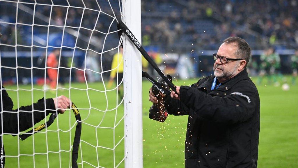 A bicycle lock being removed from a goal post by a power saw