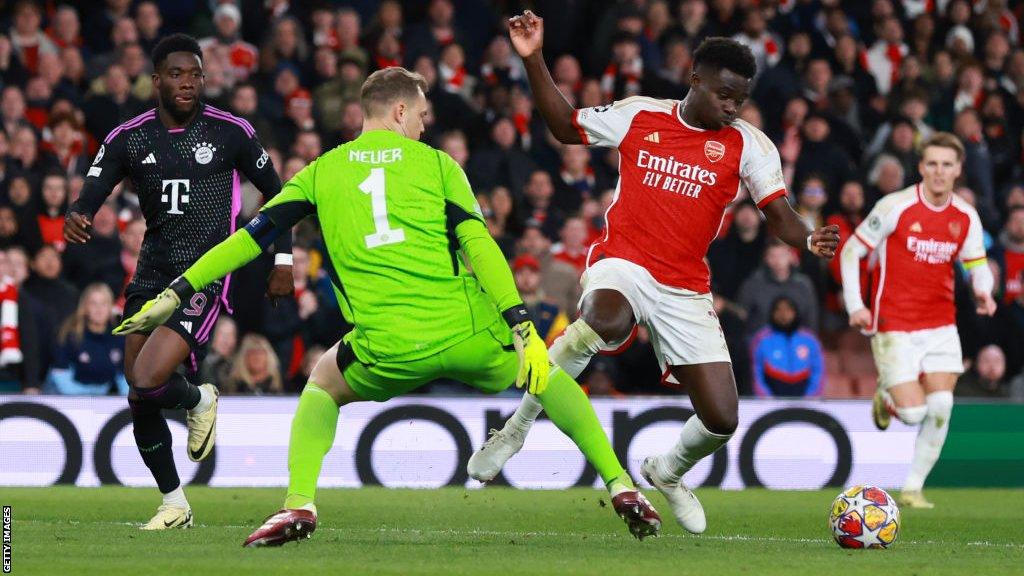 Bukayo Saka set to round Bayern Munich goalkeeper Manuel Neuer but is caught by his leg