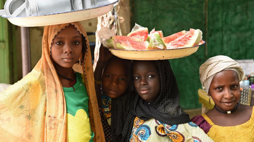 Women at a market in Chad - one with a platter of watermelon pieces on her head