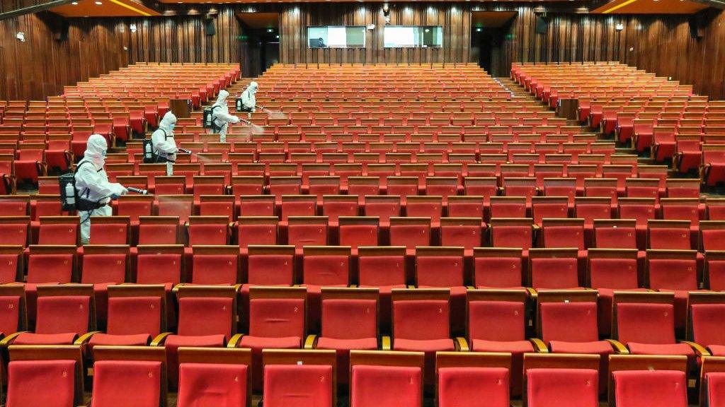 staff members spraying disinfectant at a theatre as it prepares to reopen.