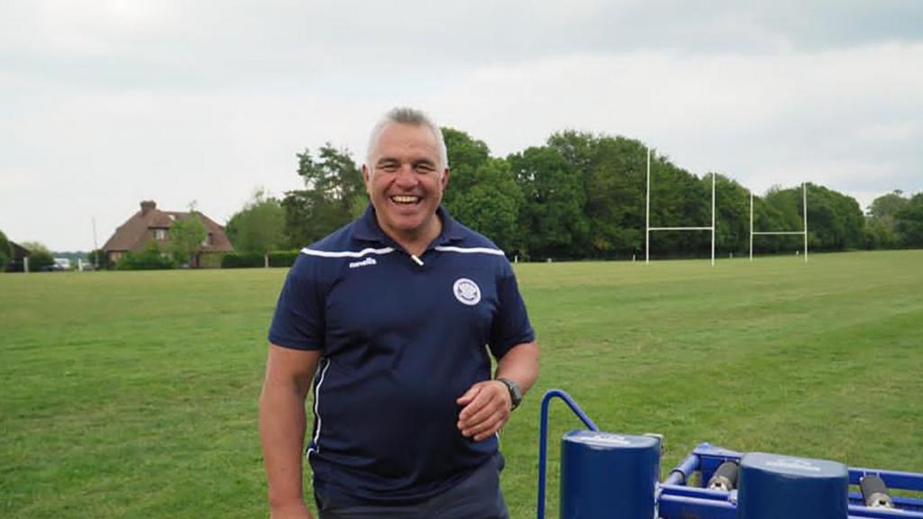 A smiling Matiu Ratana stands next to a rugby pitch