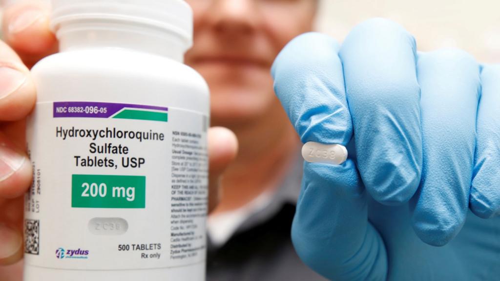 A researcher holds up a hydroxychloroquine tablet