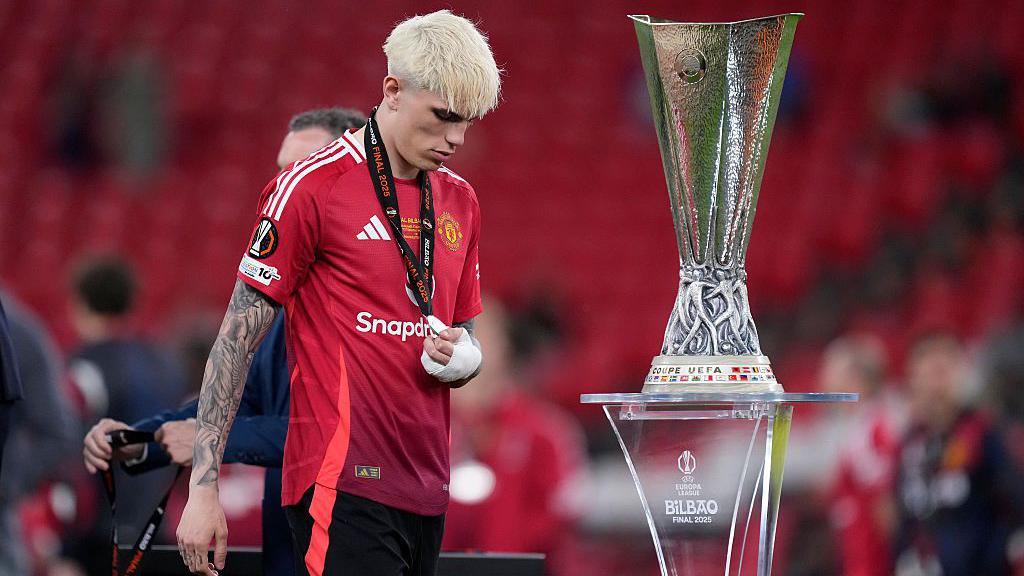 Alejandro Garnacho walks past the Europa League trophy