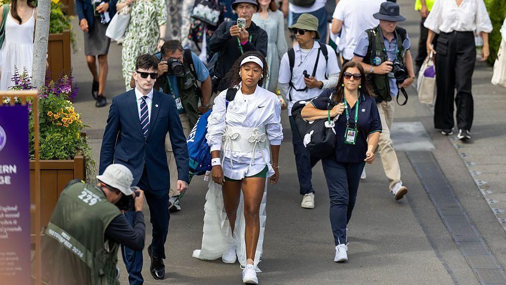Naomi Osaka walks through the Wimbledon grounds