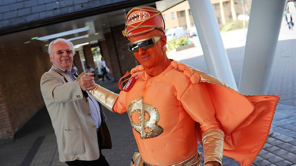 Captain Beany (R) leader of the New Millennium Bean Party, meets a potential voter on his way to register his election nomination at the council offices in Port Talbot, Wales on April 16, 2010