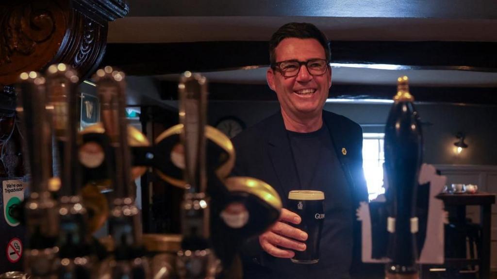 Andy Burnham holding a pint
