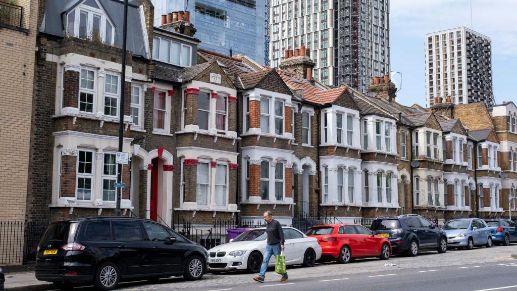 Terrace of low-rise homes with high-rise block towers behind in Tower Hamlets