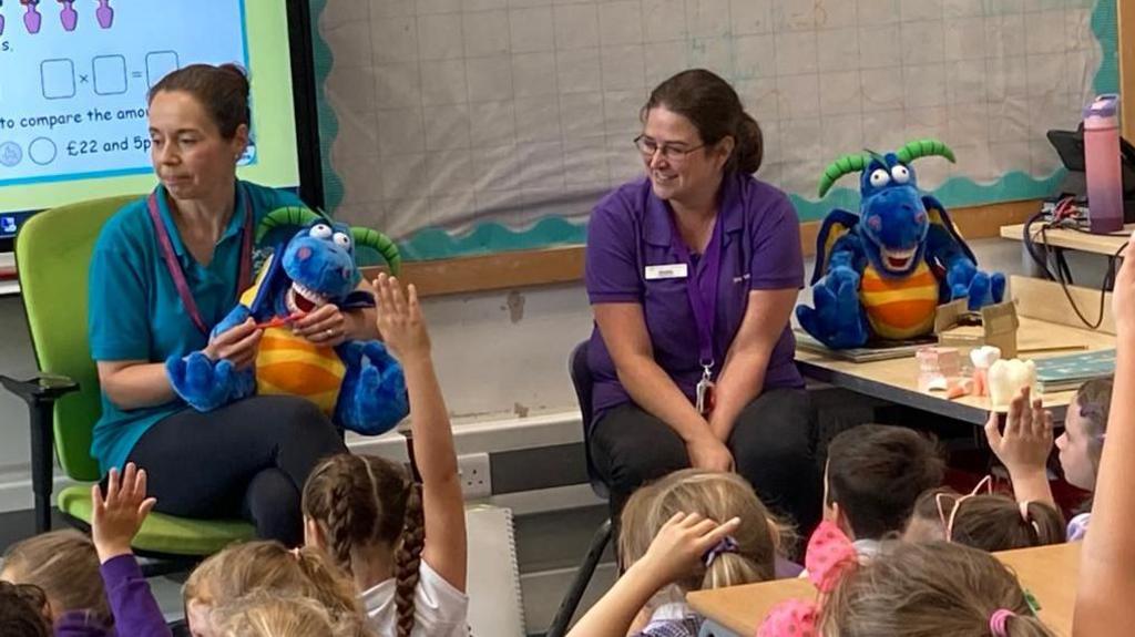 Children receiving dental hygiene tips from Smile Together and mascot Dylan