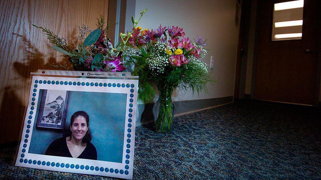Picture of Becky Zerlentes sits beside a bouquet of flowers in a corridor