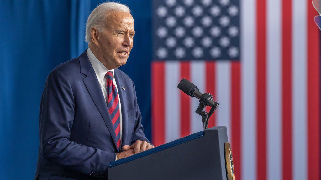 Joe Biden speaking at a lectern with the American flag behind him