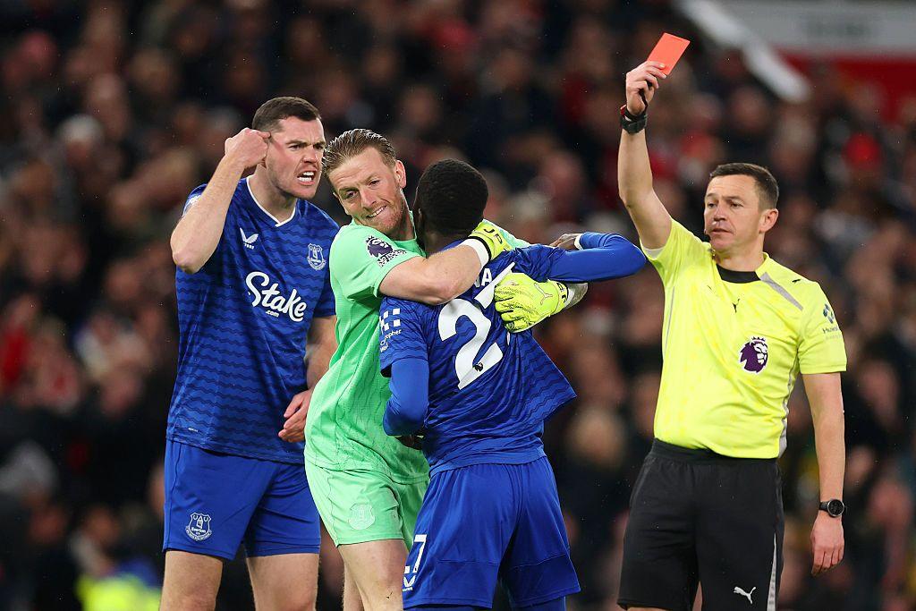 Idrissa Gana Gueye of Everton is shown a red card by Referee Tony Harrington after clashing with teammate Michael Keane as he is restrained by Jordan Pickford.