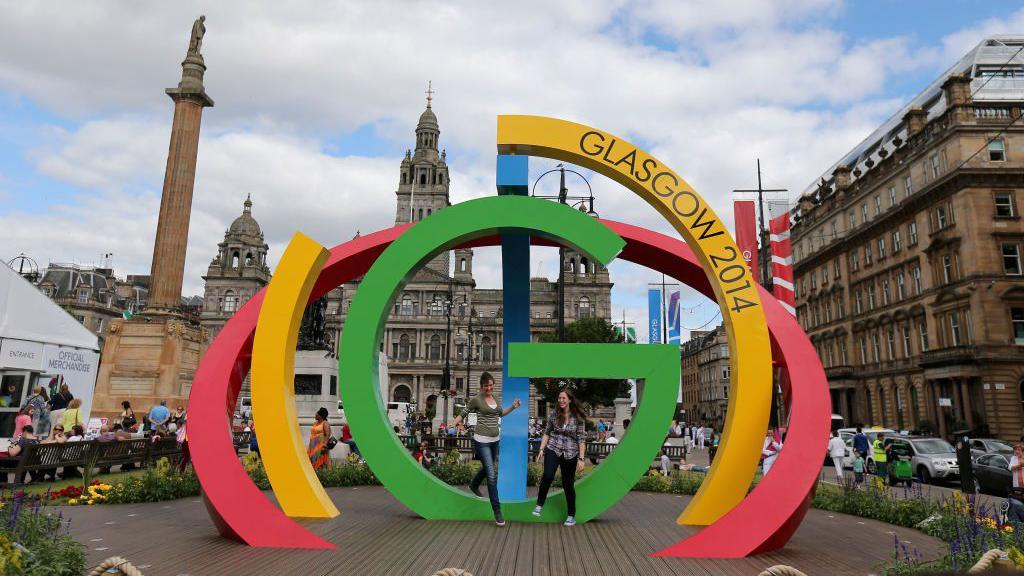 Visitors climb on the Big G sculpture in George Square, Glasgow ahead of the Commonwealth Games 2014