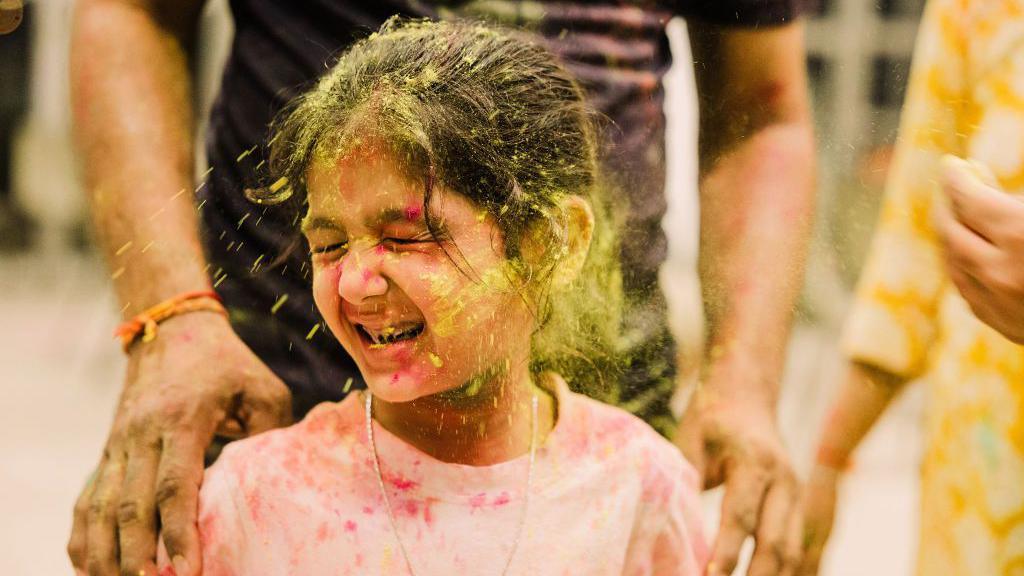 Girl with yellow coloured powder thrown at her