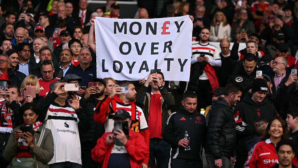 Manchester United fans hold up a sign reading 'money over loyalty' in a protest against ticket price rises at a Premier League match