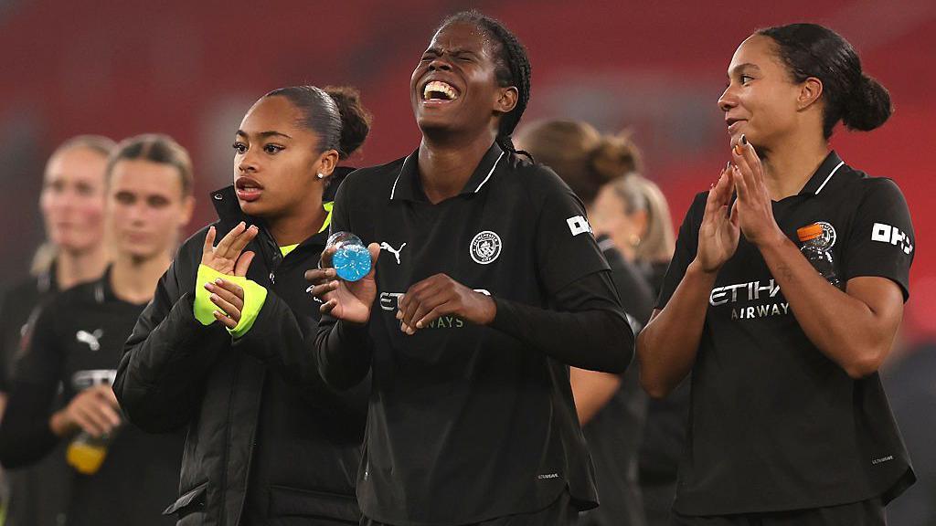 Khadija Shaw smiles with her team-mates around her
