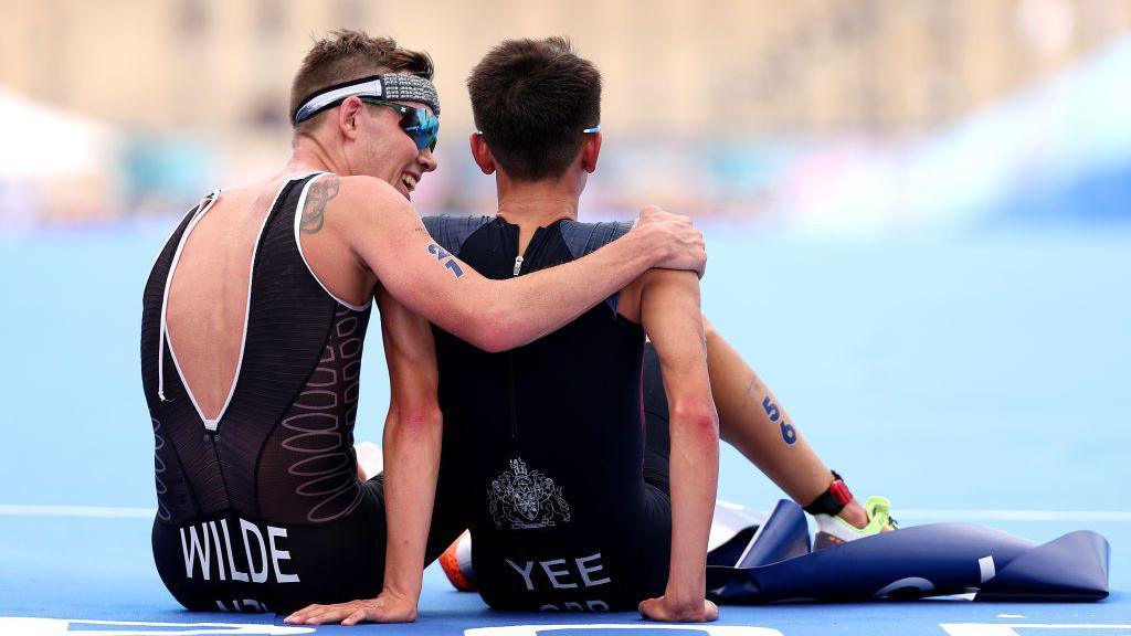 Hayden Wilde gives Alex Yee a hug after the men's triathlon.