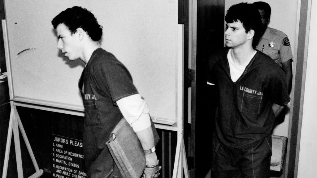 A photo from the brothers' original trial. Both brothers are wearing prison jumpsuits and are being led into court.