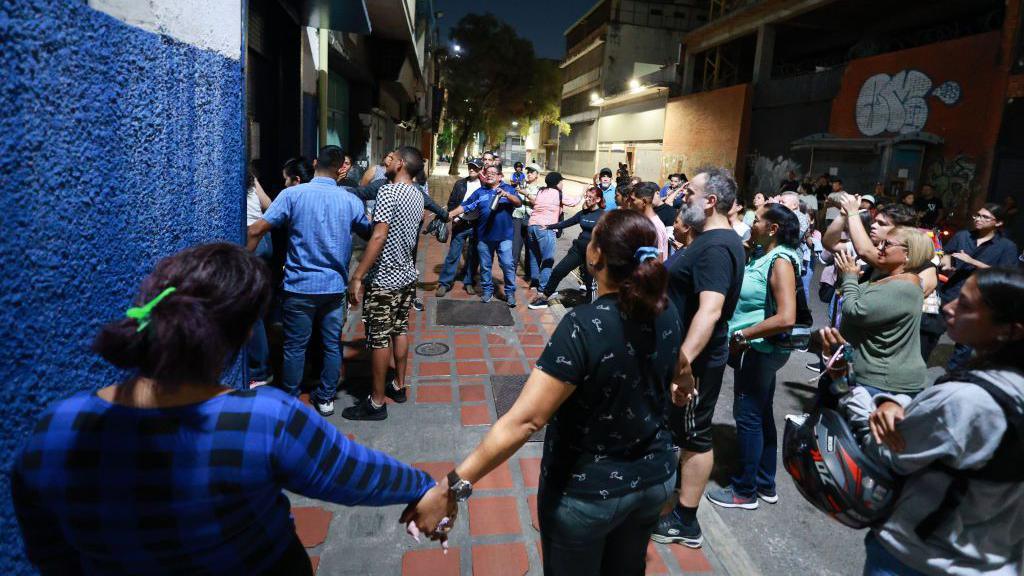 A group of people hold hands in protest to be let in to count the votes during the presidential election on July 28, 2024 in Caracas, Venezuela. 