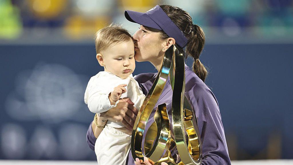 Belinda Bencic holds the Abu Dhabi Open trophy and her daughter Bella