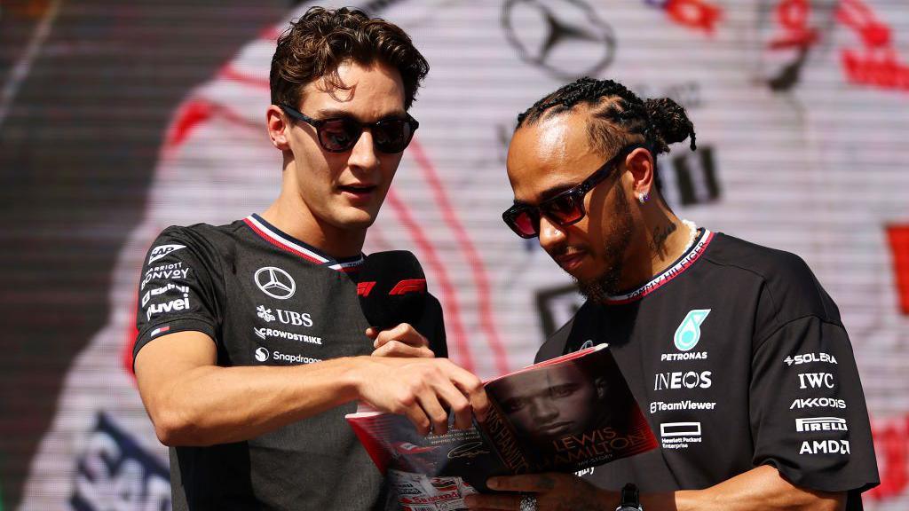 Lewis Hamilton signs his autobiography for George Russell