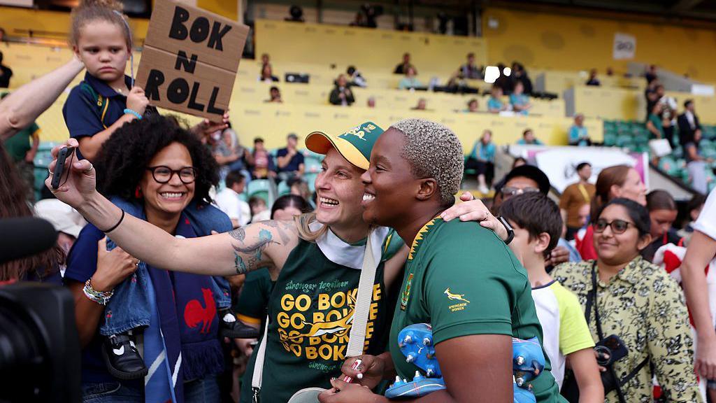 A South African rugby player poses for selfies with fans.