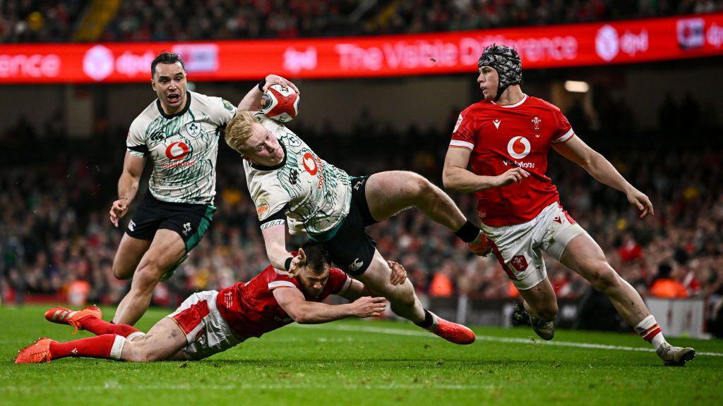 Jamie Osborne of Ireland is tackled by Tomos Williams of Wales during the Guinness Six Nations Rugby Championship