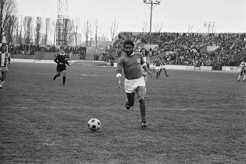 Benfica legend Eusebio runs with the ball during a football match.