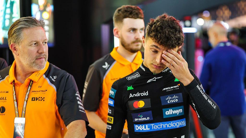 Lando Norris walks back to the paddock after his qualifying crash