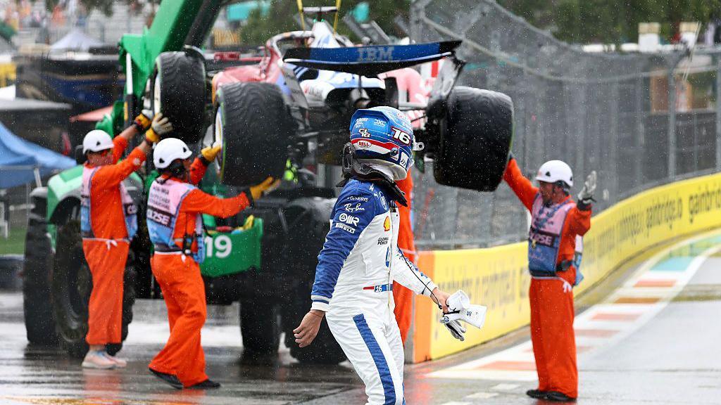 Charles Leclerc looks back at his Ferrari as it's lifted onto the recovery truck