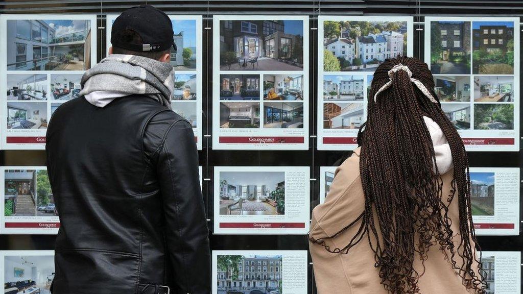 Young couple looking at an estate agent's window