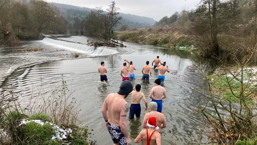 Group of men entering a lake to swim