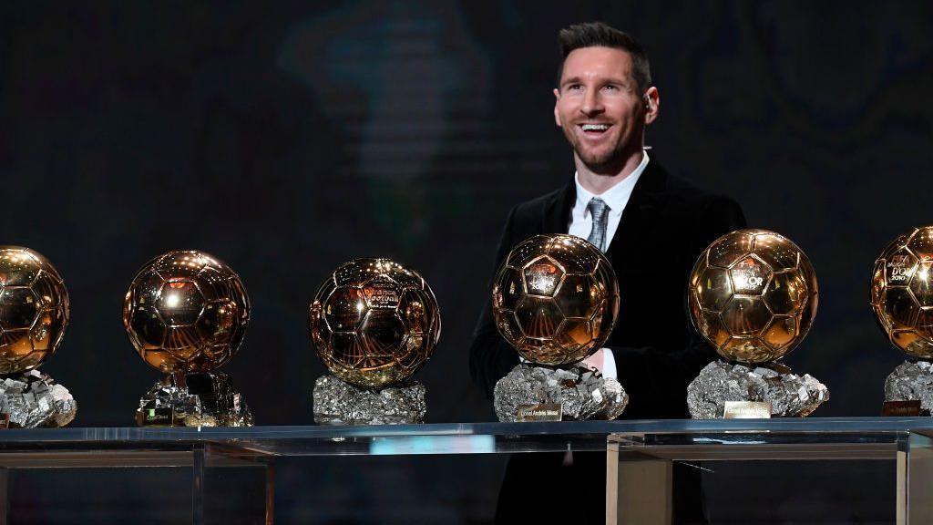 Lionel Messi posing with six of his Ballon d'Or awards.