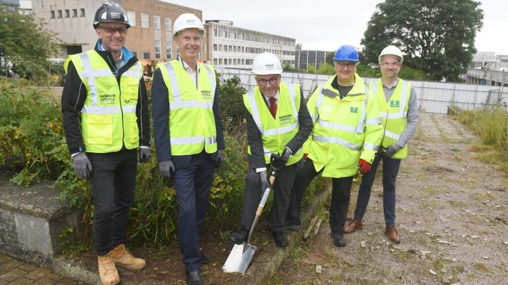 Tudor Evans, leader of Plymouth City council, with a spade and wearing a hi-vis gilet with four other men all wearing hi-vis.