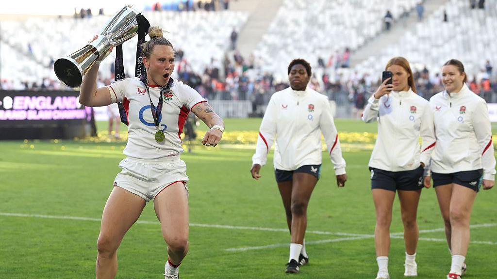 meg jones dancing with six nations trophy while other England players look on and take photos of her