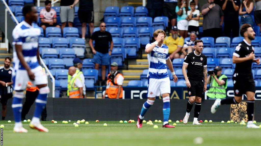 Reading players walk away from tennis balls that were thrown on to the pitch in protest at the Select Car Leasing Stadium during a League One match.