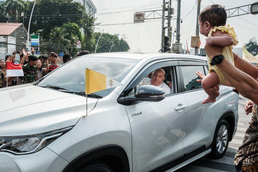 A man holds his baby for Pope Francis to bless