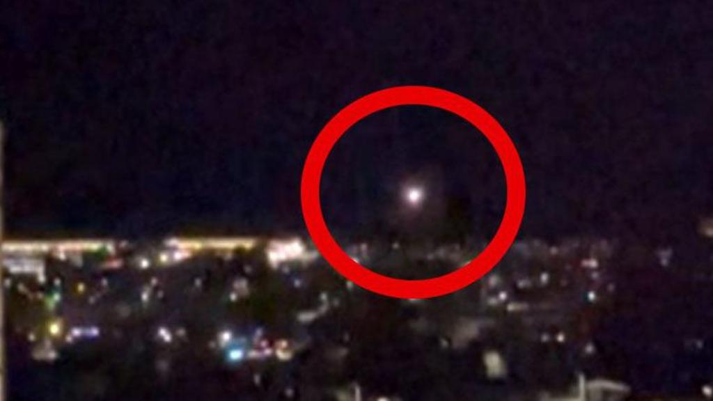 A red circle highlighting a drone flying over the night sky 