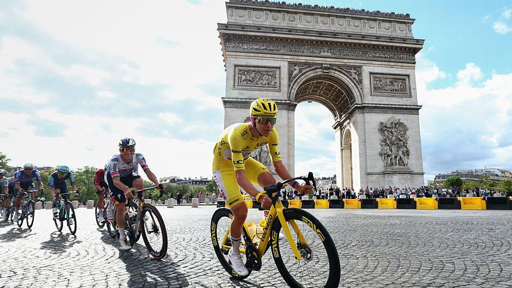 Tadej Pogacar rides past the Arc de Triomphe