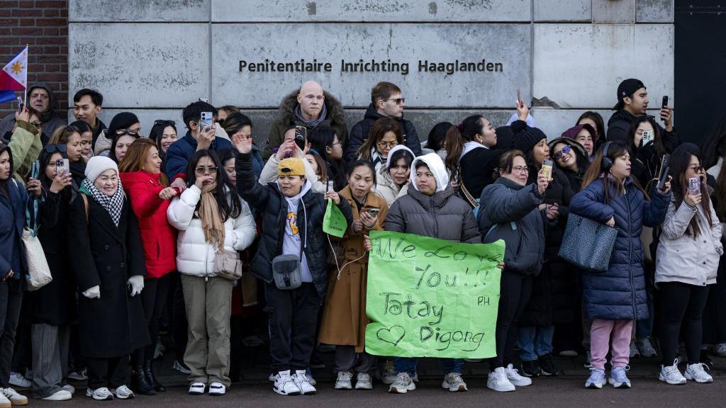 A group of Duterte supporters gather outside the detention centre in Scheveningen, The Hague. One of them holds up a green banner that reads, "We love you!"