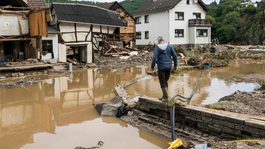 A man walks through the floods towards destroyed houses in Schuld near Bad Neuenahr, western Germany, on 15 July 2021.