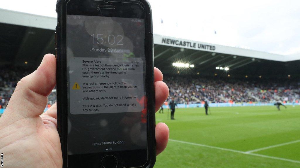 A fan holding a phone at St James' Park