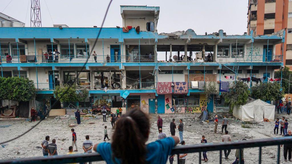 A Palestinian girl looks at a UN school in Nuseirat refugee camp, in the central Gaza Strip, which was damaged in an Israeli strike (6 June 2024)