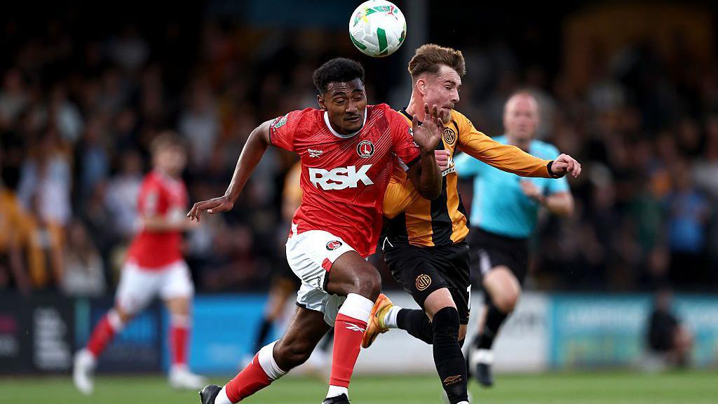 Joshua Laqeretabua of Charlton Athletic competes for a header with Ben Knight of Cambridge United