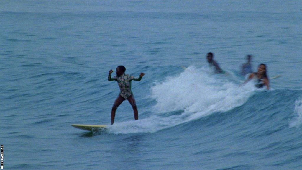 Vanessa Turkson catches a wave, cheered on by her fellow surfers