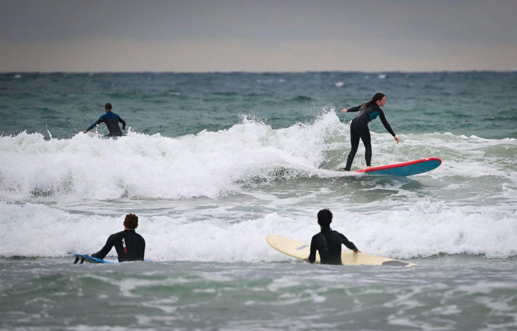 Surfers enjoying the waves in the sea at Polzeath beach in Cornwall